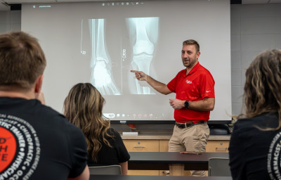 The team physician presents an x-ray to pre-health students.