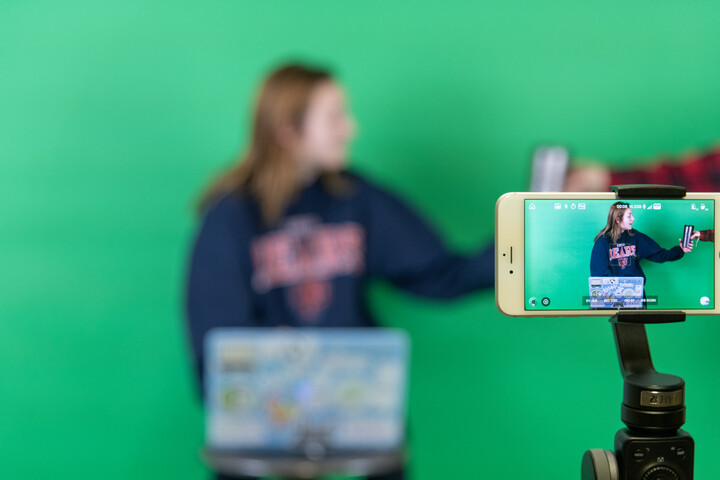 Student filming in front of green screen