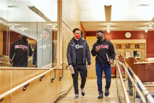 Students in masks walking in the Clausen Center.