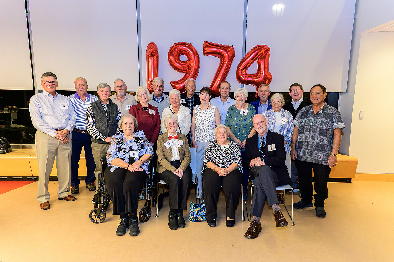 A group of people from the graduating class of 1974 in front of a red 1974 balloon.