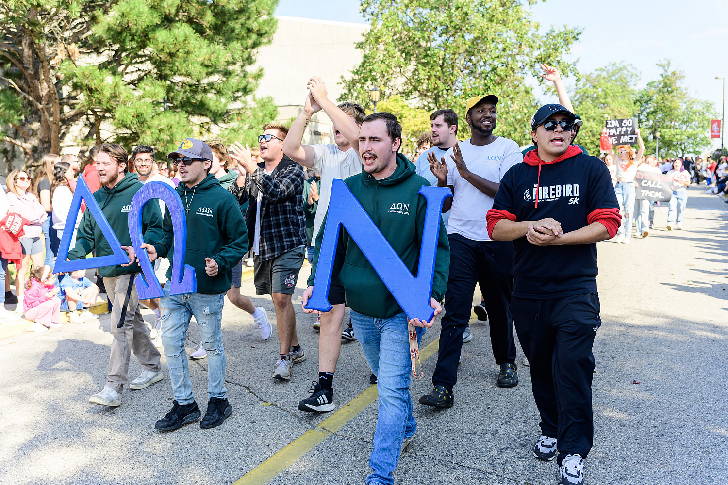 A group of male students holding signs and walking on a paved road.