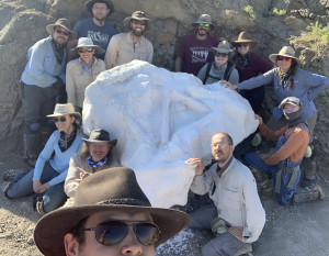 Expedition volunteer session team at the field jacket that contains a triceratops skull. Clockwis...