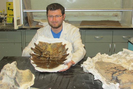 Brady Holbach ?20 in the Carthage Institute of Paleontology laboratory, proudly holding a spectac...