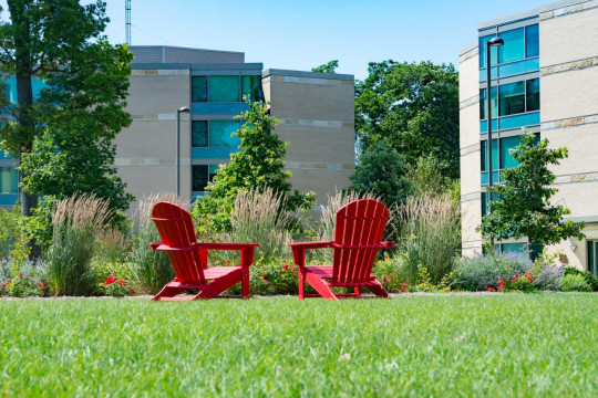 Red chairs in front of The Oaks Residence Halls.