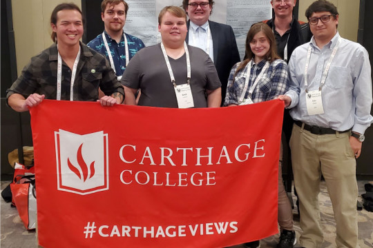 A group photo of the Carthage attendees and presenters in front of Nathan Cochran?s poster. From ...