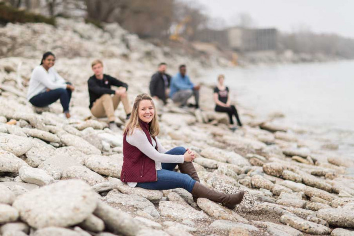 Students gather on the rocks by the lakeshore