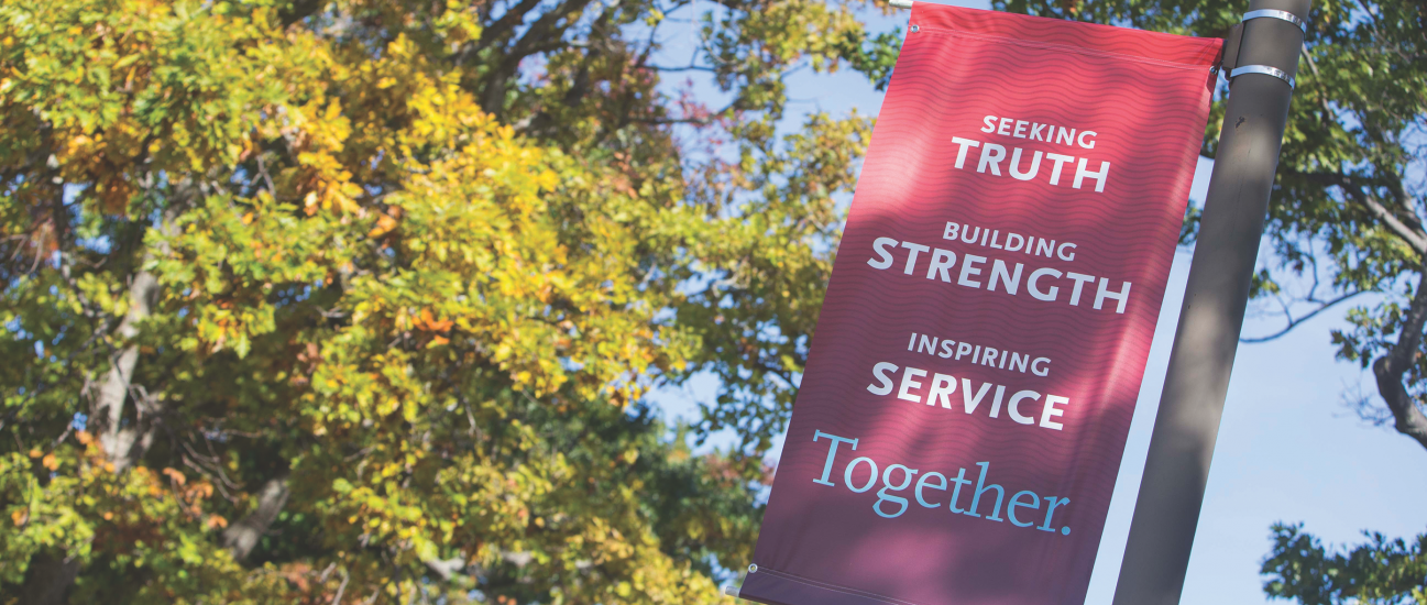 A banner on Campus Drive displays the Carthage College mission statement: Seeking Truth, Building...