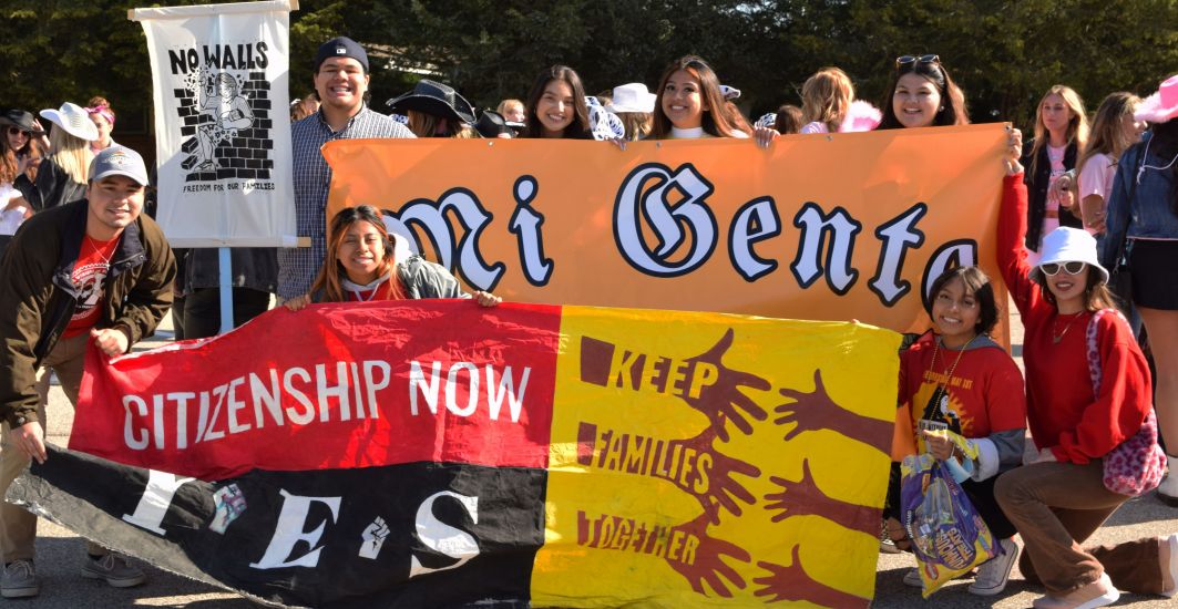 Students in the student org Mi Gente carry their banners and signs at the 2021 Homecoming Parade. 