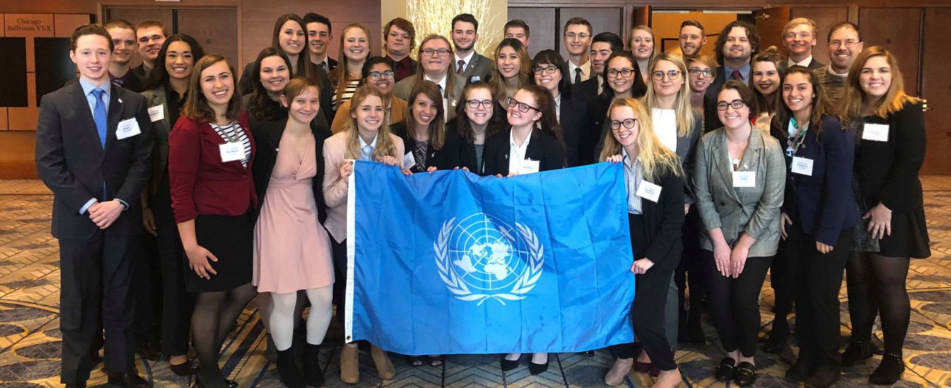 The Model UN team poses at a conference with their logo. 