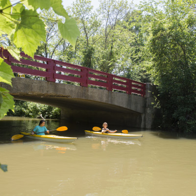 Students kayak along the Pike River under Carthage?s red bridge.