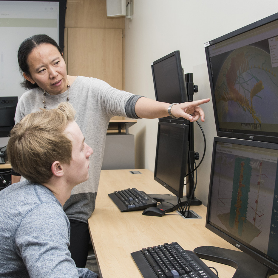 Professor Wenjie Sun works with a student on a GIS project.