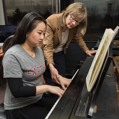 A student gets assistance on the piano from a faculty member.