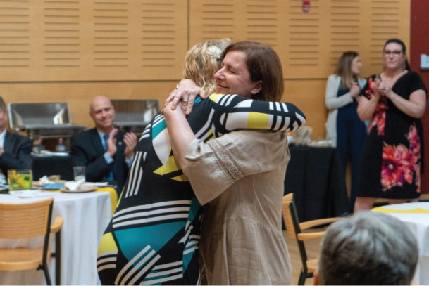 Professor Julie Dawson, right, hugs faculty colleague Laura Huaracha after receiving the 2022-23 ...